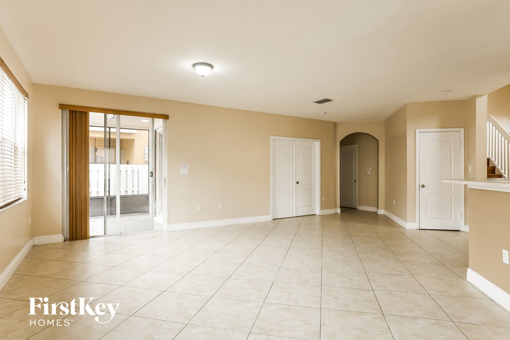 A spacious living room with a tiled floor and a staircase on the right.