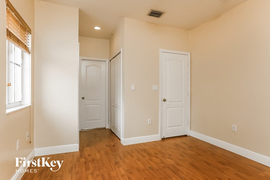 A room with wooden floors and three white doors.