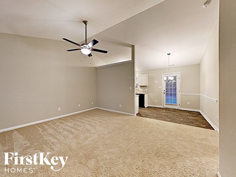 an empty living room with a ceiling fan