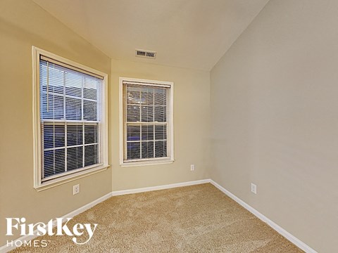 the second bedroom has a large window and beige carpeting
