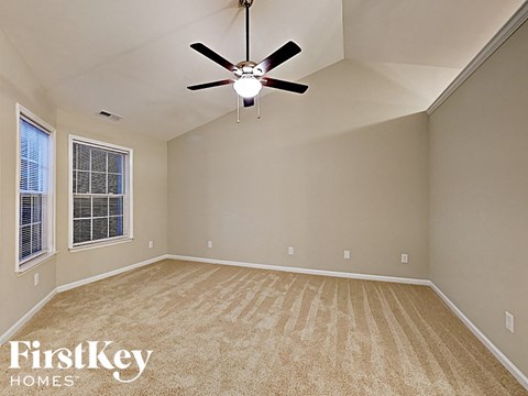an empty living room with a ceiling fan and a window