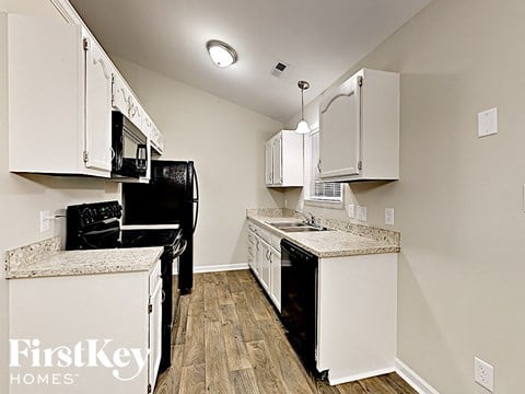 a kitchen with white cabinets and a black refrigerator