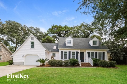 a white house with a green lawn and trees