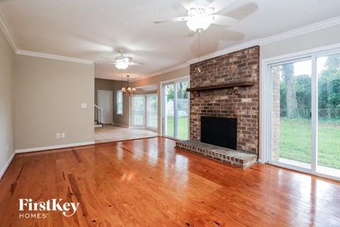 an empty living room with a brick fireplace and wood floors
