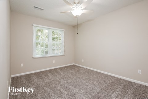 an empty bedroom with a ceiling fan and a window