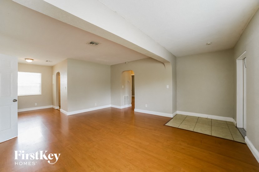 an empty living room with wood floors and white walls