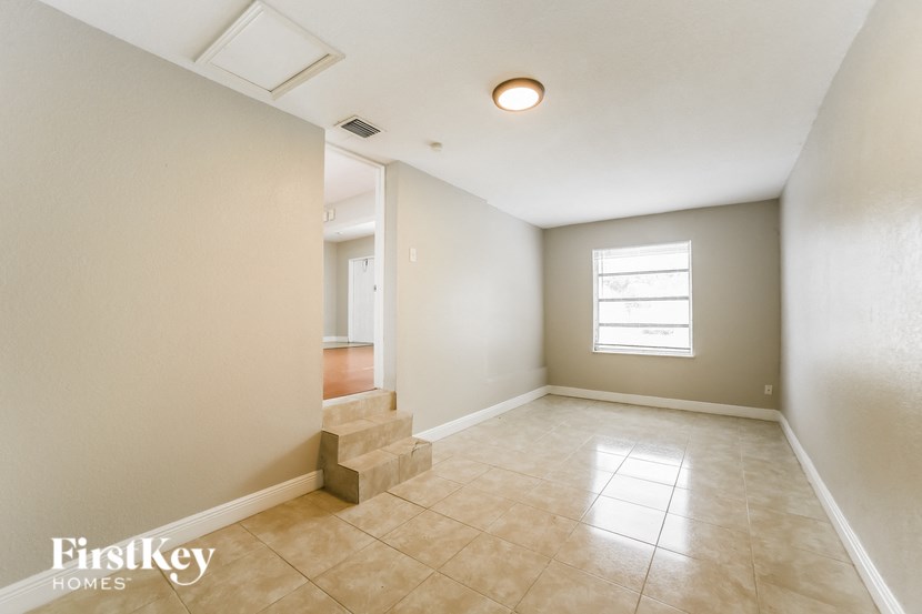 an empty living room with tile floors and a staircase