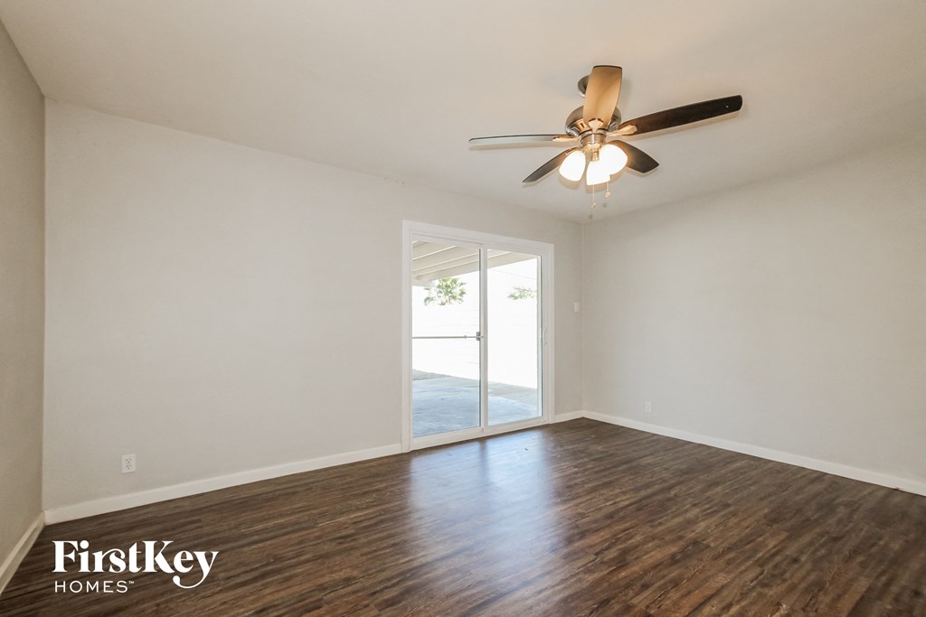 the living room of an empty house with a ceiling fan and a window