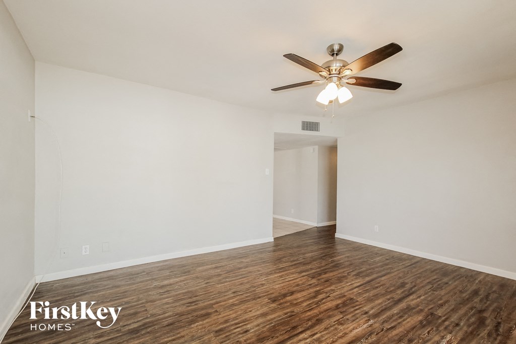 a living room with white walls and a ceiling fan