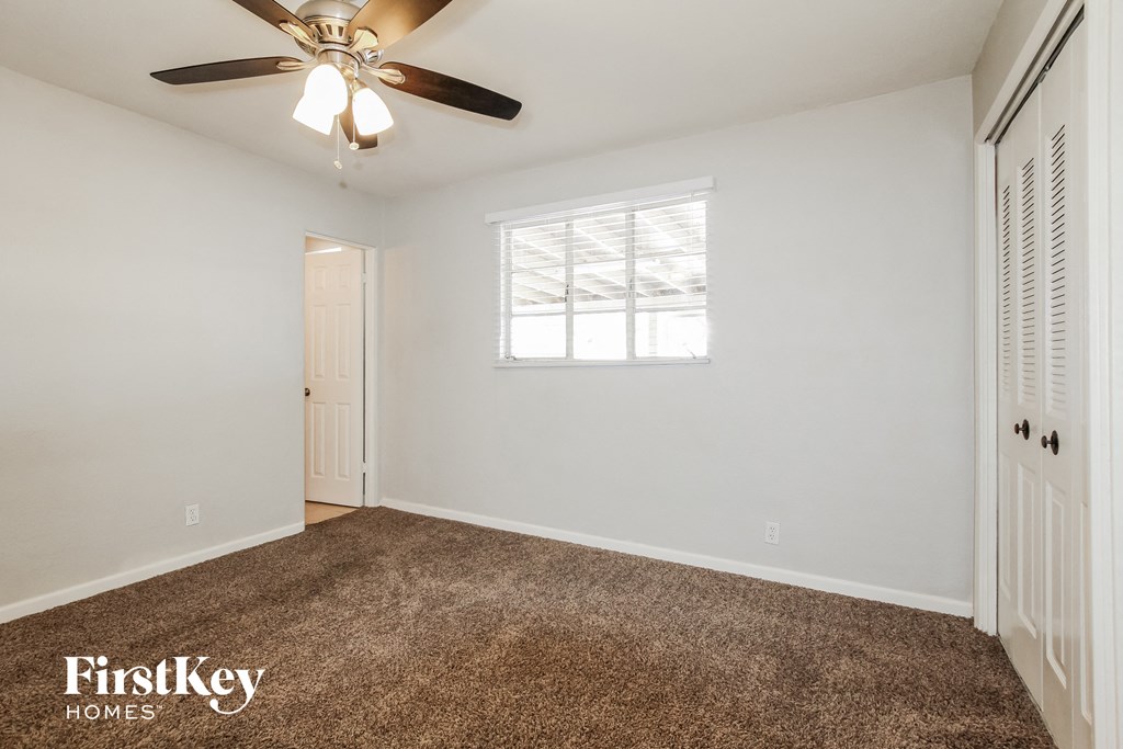 a bedroom with white walls and a ceiling fan