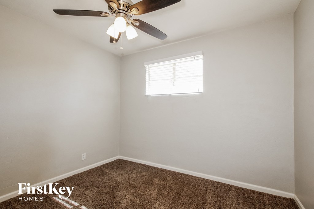 the bedroom has a ceiling fan and a carpet