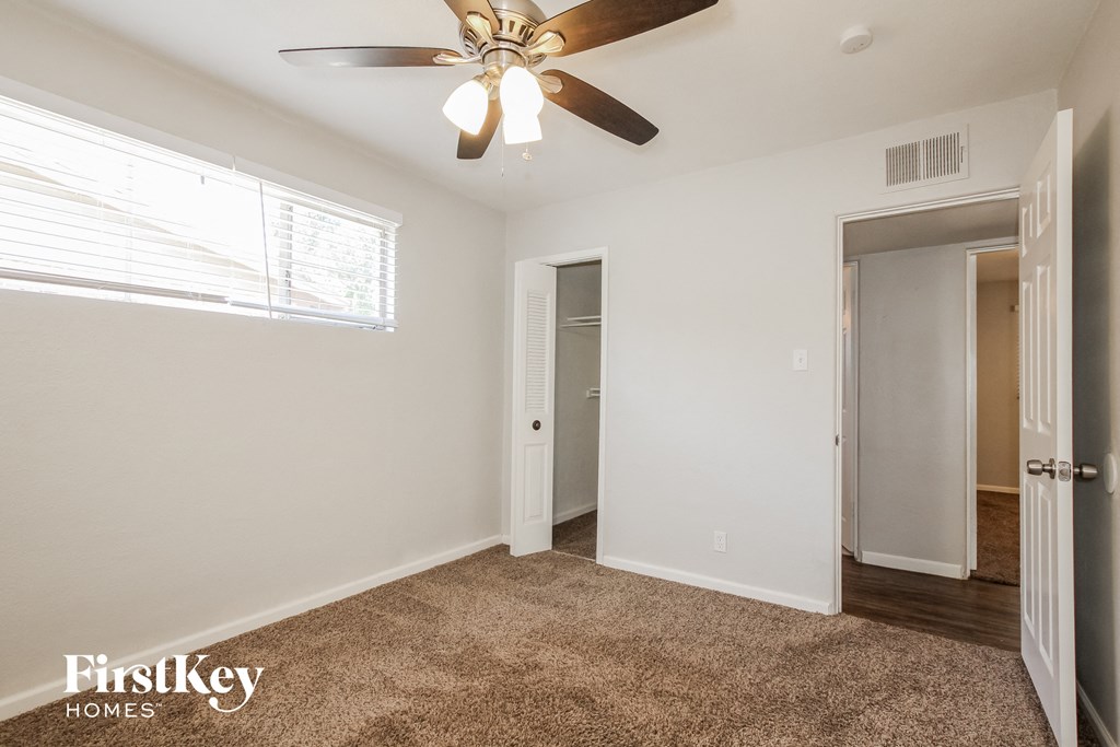a bedroom with a ceiling fan and a door to a closet