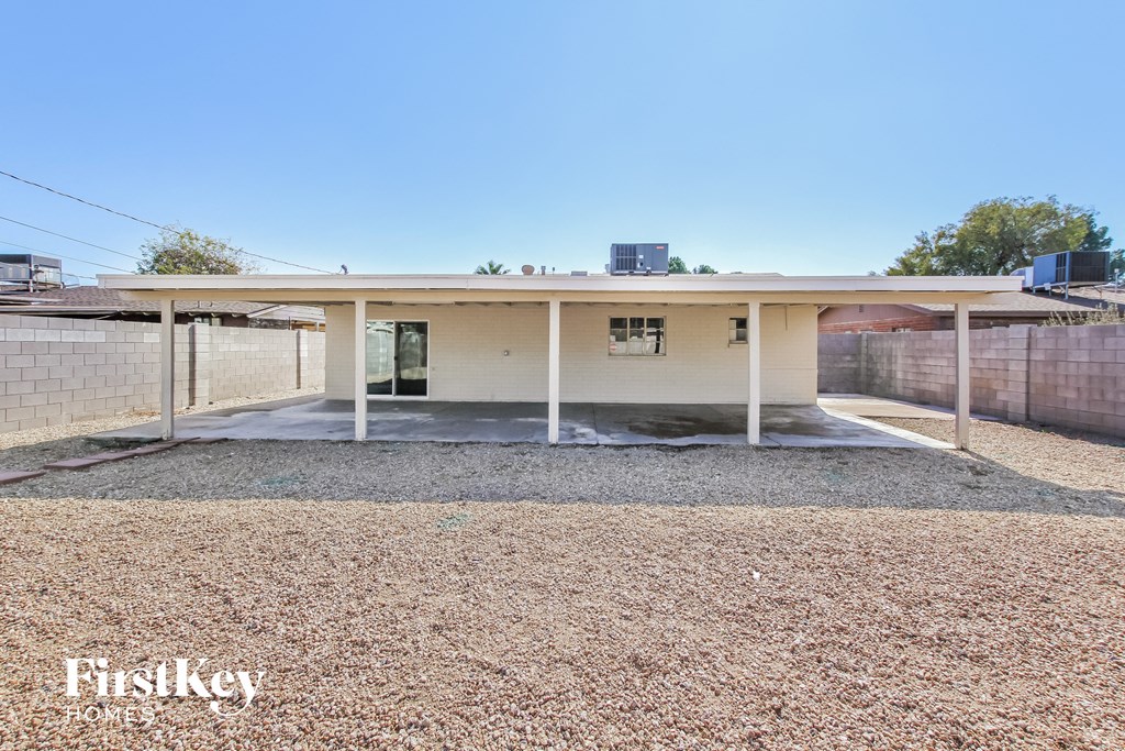 a small house with a covered porch and a brick fence