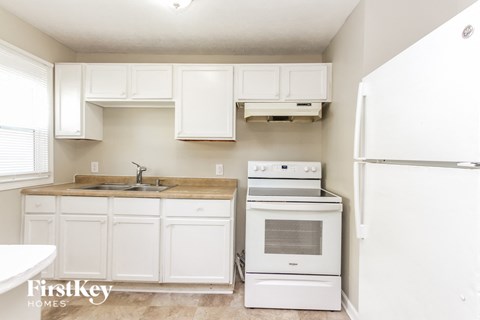 A kitchen with white cabinets and appliances.