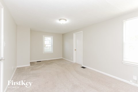 A spacious room with a carpeted floor and a window.