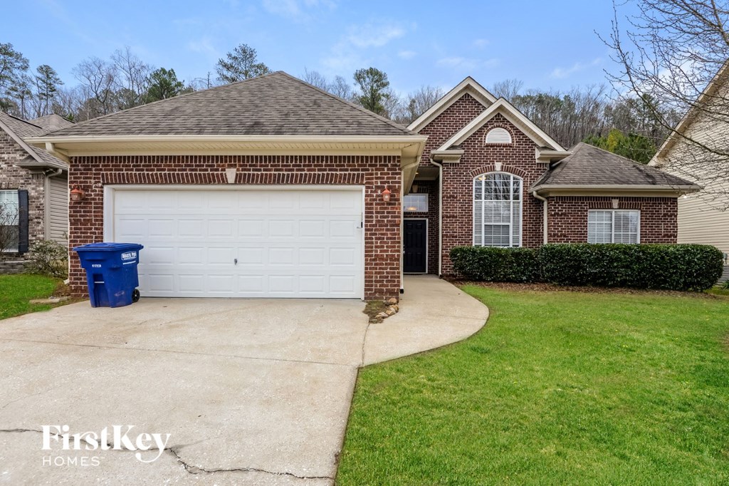 A brick house with a white garage door is for sale.