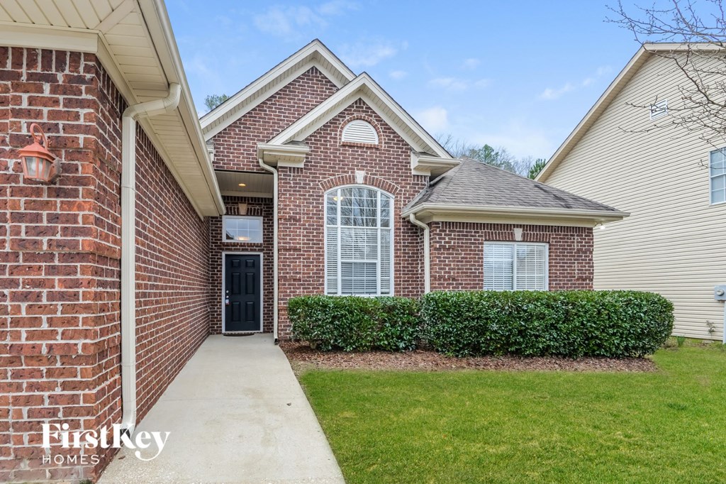 A brick house with a black door and a small window is for sale.