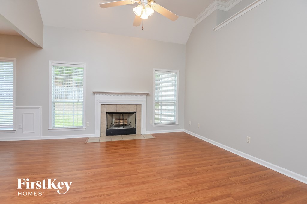 A spacious room with a fireplace and a ceiling fan.
