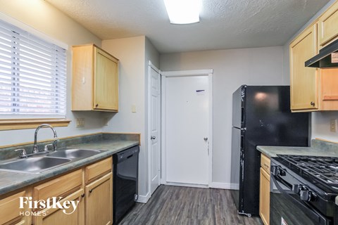 A kitchen with wooden cabinets and a black fridge.
