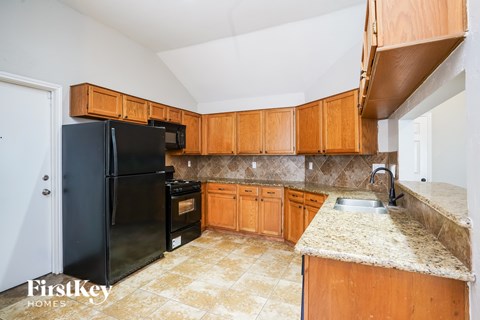 A kitchen with wooden cabinets and a black fridge.