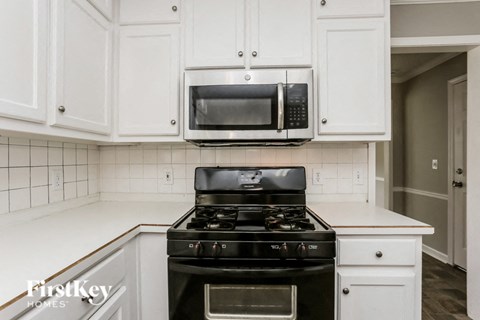a kitchen with white cabinets and a stove and a microwave
