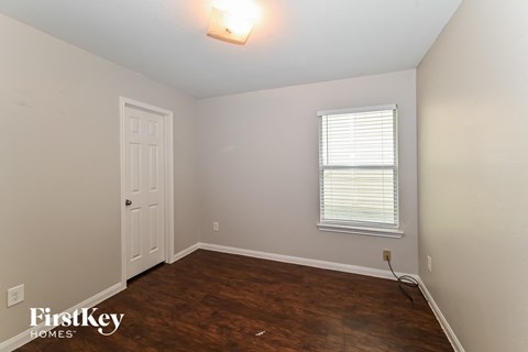 a bedroom with a wooden floor and a white door
