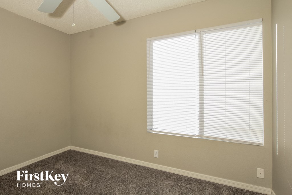 a bedroom with a large window and a carpeted floor