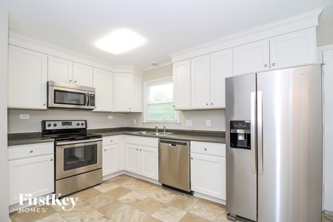 A kitchen with a stainless steel refrigerator and white cabinets.