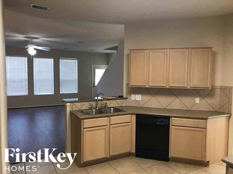 A kitchen with a black dishwasher and wooden cabinets.