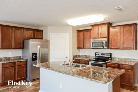A kitchen with brown cabinets and a granite countertop.