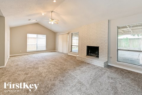 A spacious living room with a fireplace and a ceiling fan.
