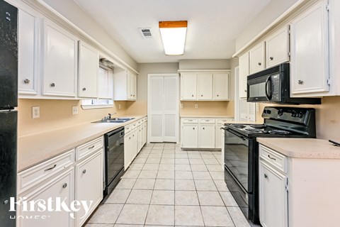 A kitchen with black appliances and white cabinets.
