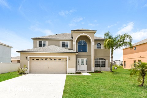 a beige house with a garage and a palm tree