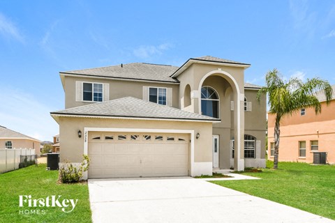 a beige house with a garage and a palm tree