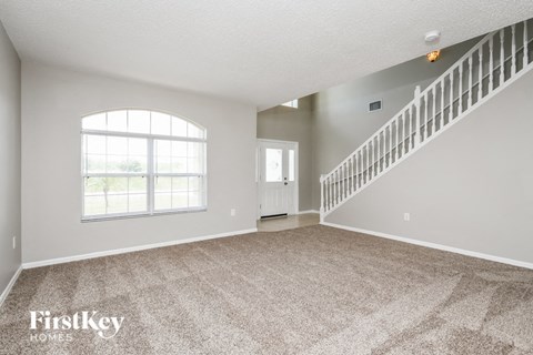 an empty living room with a staircase and a window