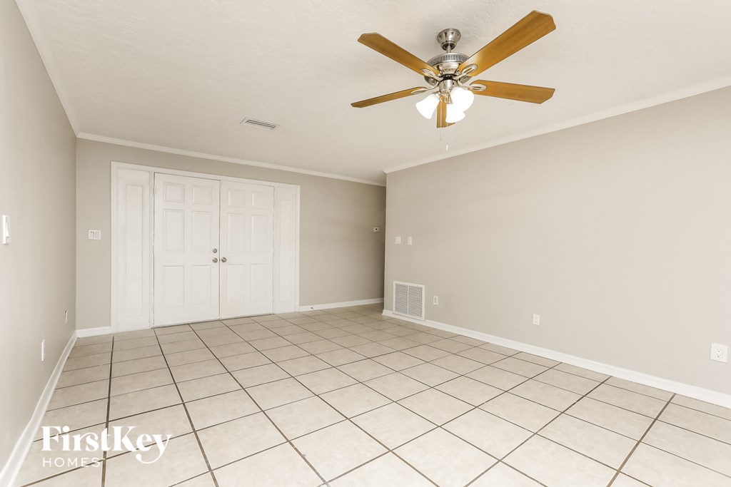A spacious room with a ceiling fan and tiled flooring.
