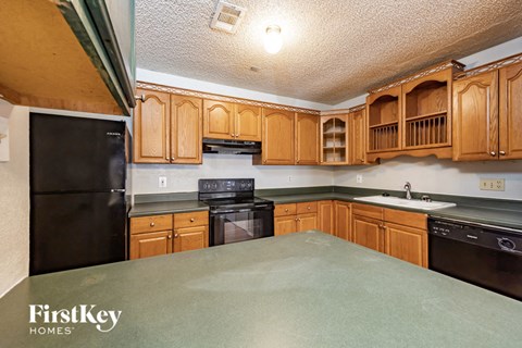 A kitchen with wooden cabinets and a black fridge.