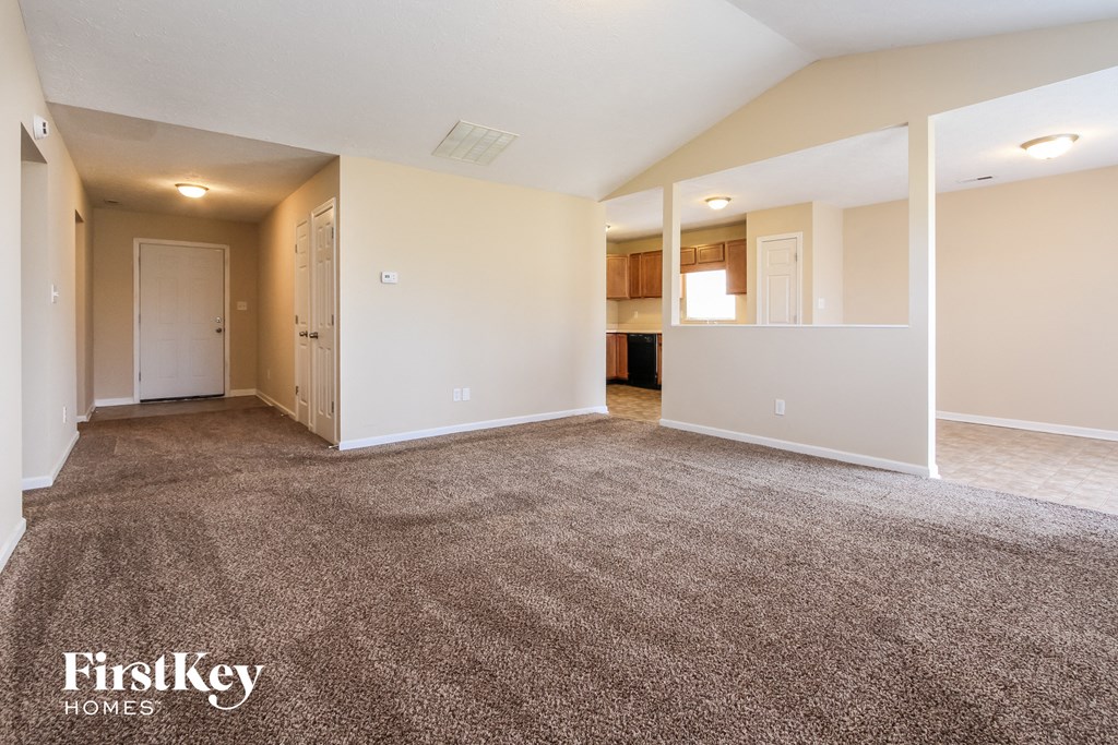 A spacious empty room with a carpeted floor and white walls.
