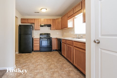 A kitchen with wooden cabinets and a black fridge.
