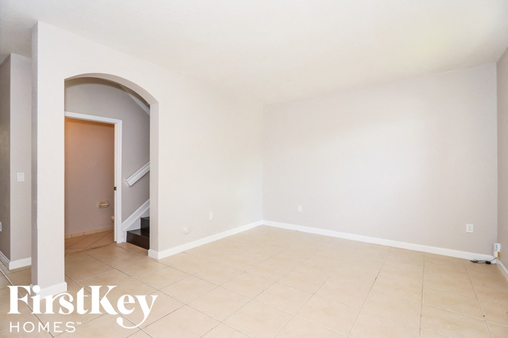 an empty living room with an arched doorway and a tiled floor