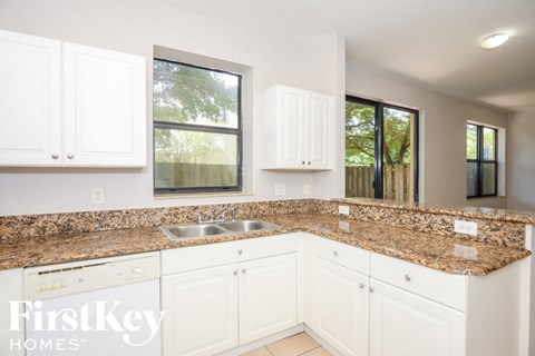 a white kitchen with granite counter tops and white cabinets