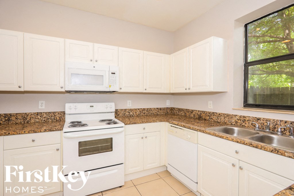 a kitchen with white cabinets and white appliances and granite counter tops