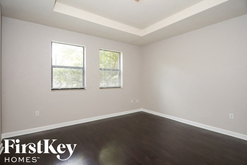 an empty room with wood floors and two windows