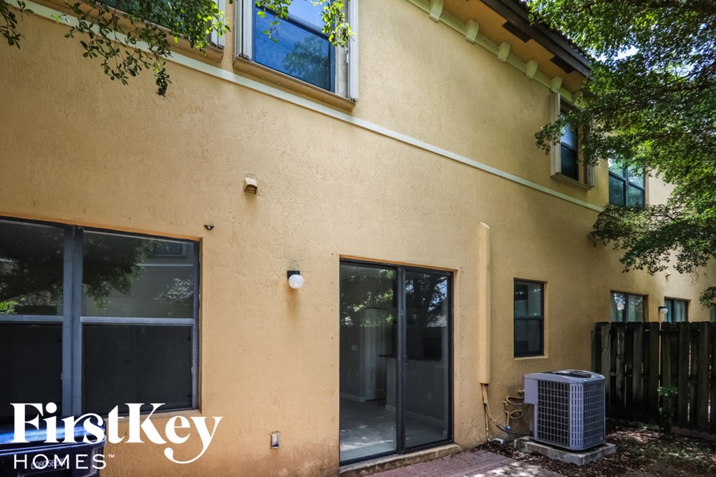 the outside of a house with two doors and a air conditioning unit