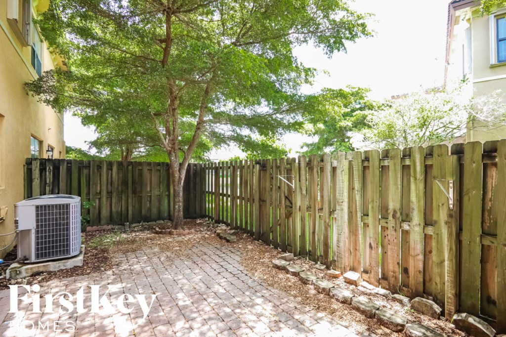 a backyard with a fence and a tree and a air conditioner
