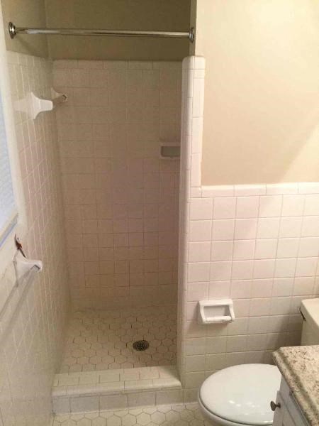 a small white bathroom with a shower and a toilet