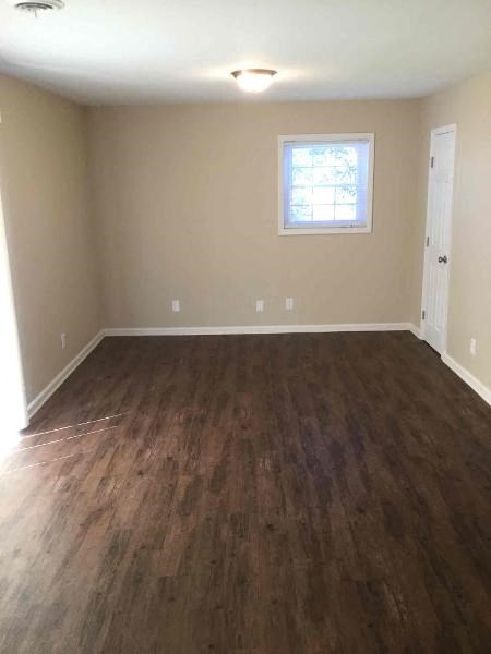 an empty living room with wooden floors and a window