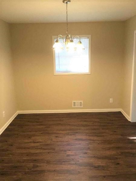 a empty living room with wood floors and a chandelier