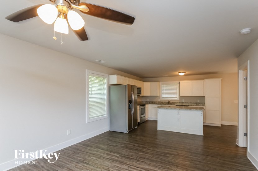 A spacious kitchen with a ceiling fan and wooden flooring.
