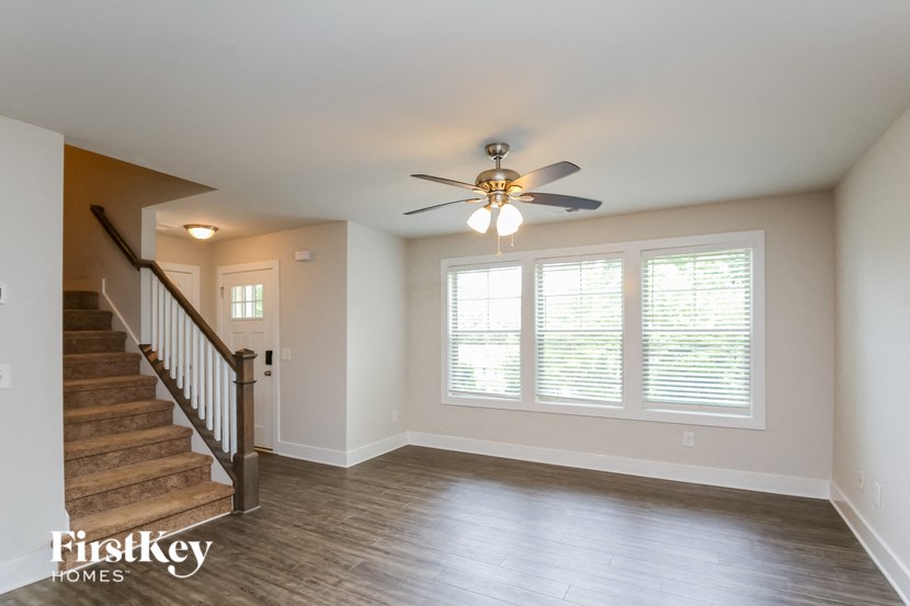 A spacious room with a staircase and a ceiling fan.